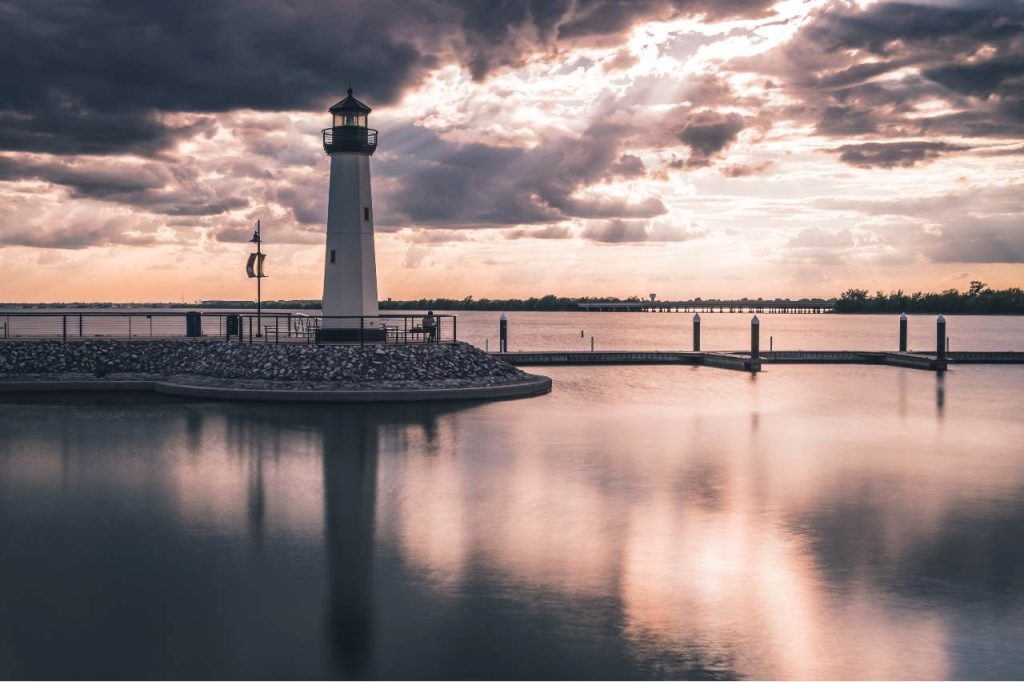Sun breaks through the clouds above the lighthouse at The Harbor in Rockwall, TX, on Lake Ray Hubbard