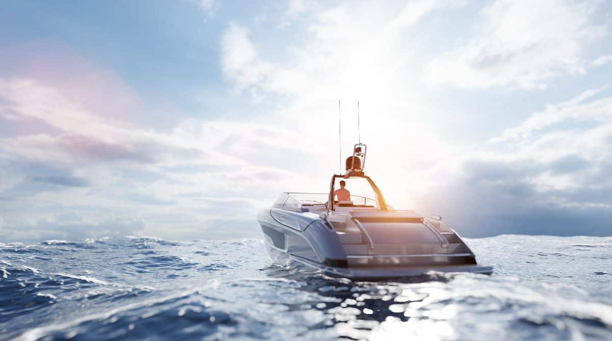 A white boat floats on the waves in open water on a bright, partly cloudy day.