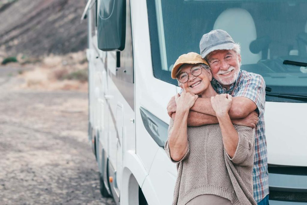 An older couple hugging outside of their RV