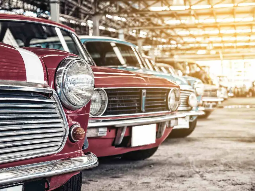 A row of classic cars sit covered in storage