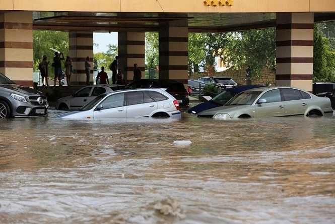 Vehicles and a building are flooded in a city due to flooding from heavy rain.