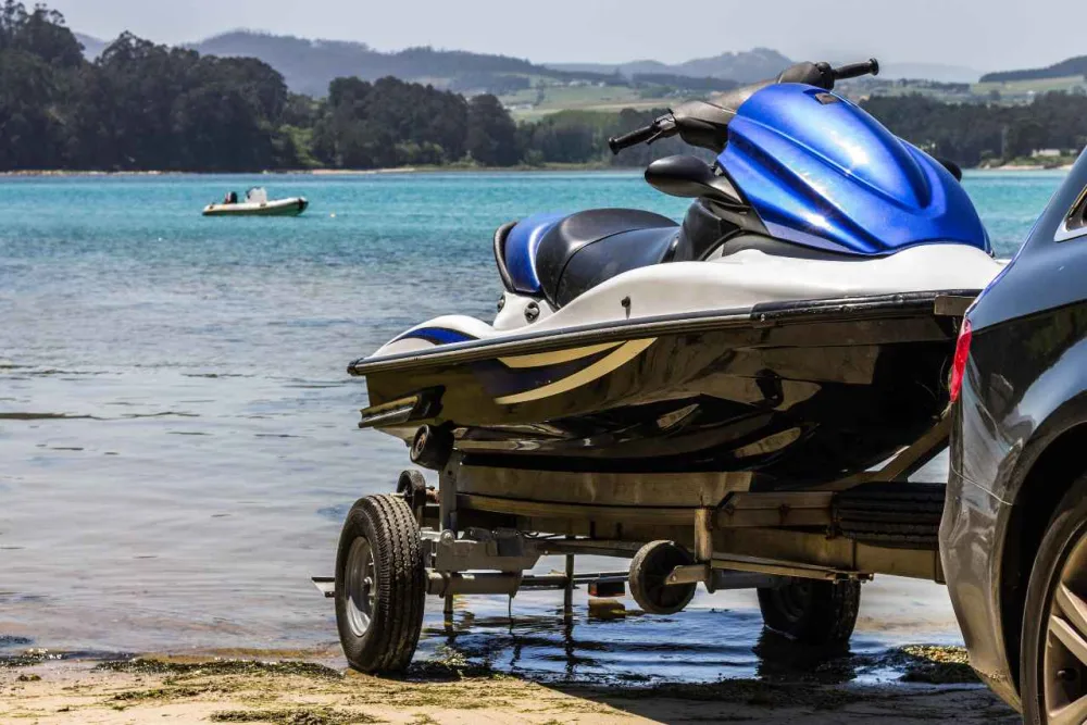 A personal watercraft is pulled from the water on a trailer to go into storage.