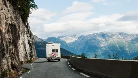 An RV traveling down a road in a beautiful mountainous area.