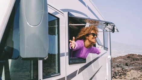 A woman with her head and arms out of the window of an RV