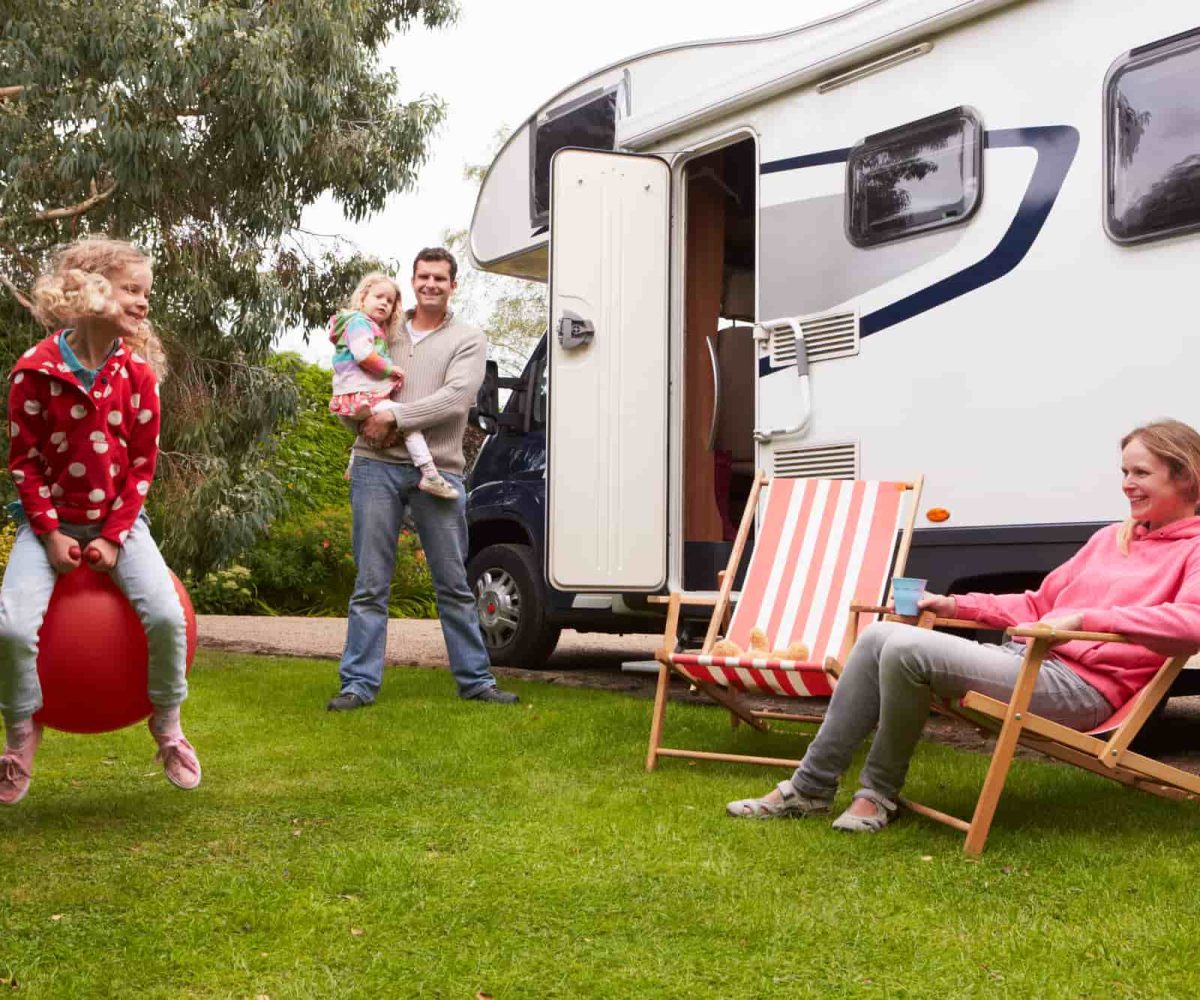 A family enjoying time outside the RV they’re renting for vacation.