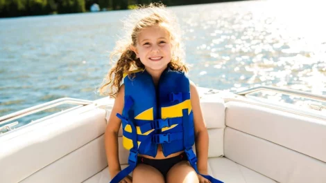 a young girl smiling and wearing her life jacket on the boat