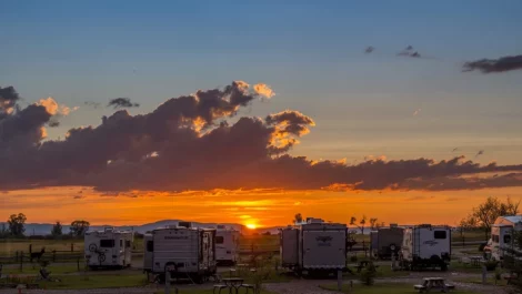 A collection of RV's facing the sunset in an RV park