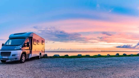 An RV parked next to a lake at sunset