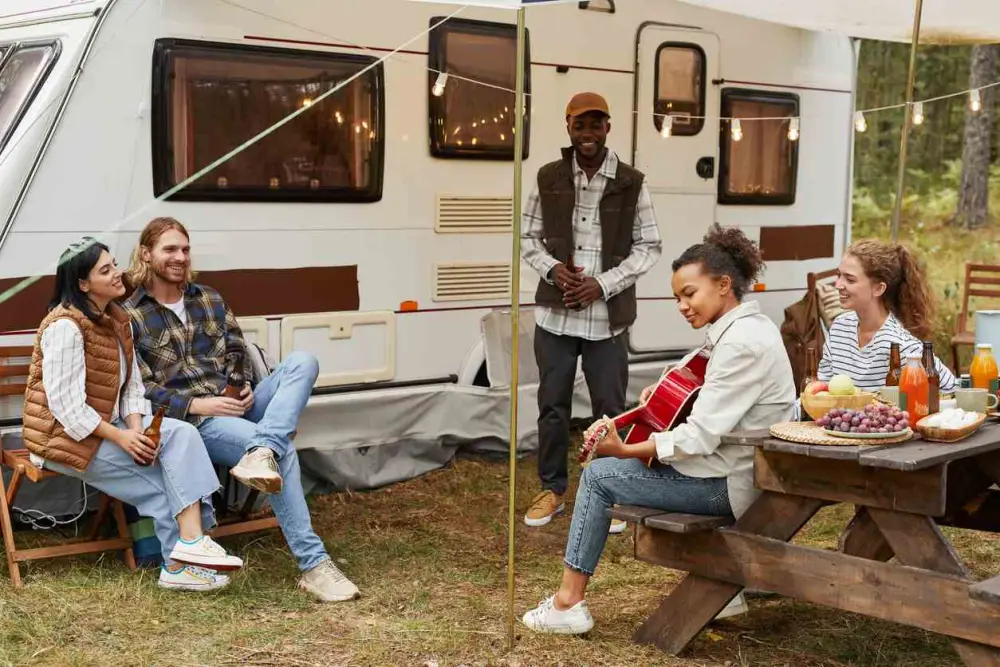 A group of friends outside an RV singing and playing guitar