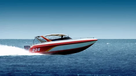 A red, white, and yellow speedboat cruising on the water