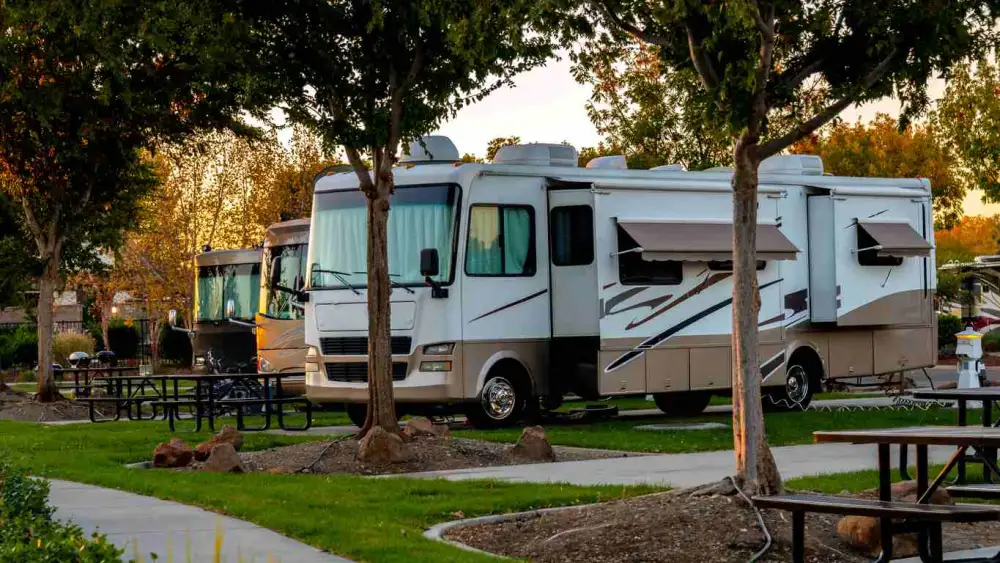 An RV in sun surrounded by tree's and trails