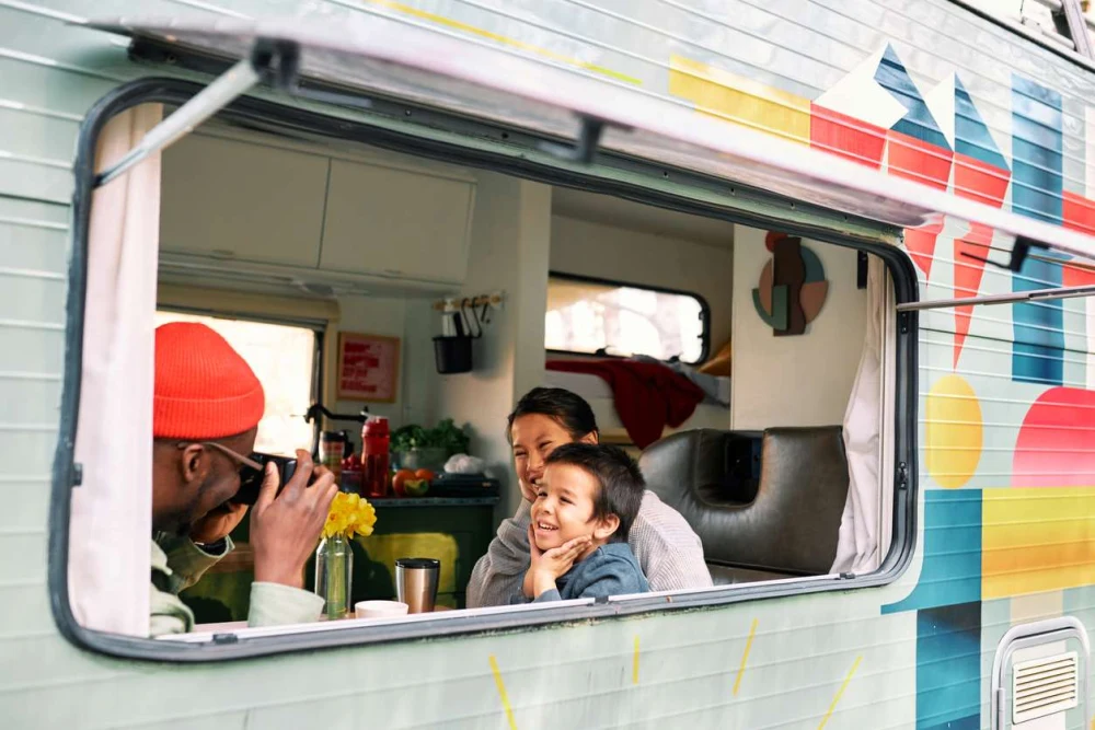 A family smiling through the window of an RV