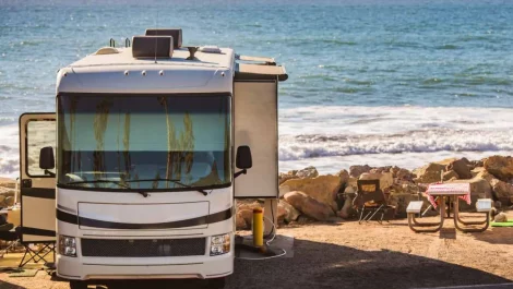 An RV set up with a picnic table on the lake beach