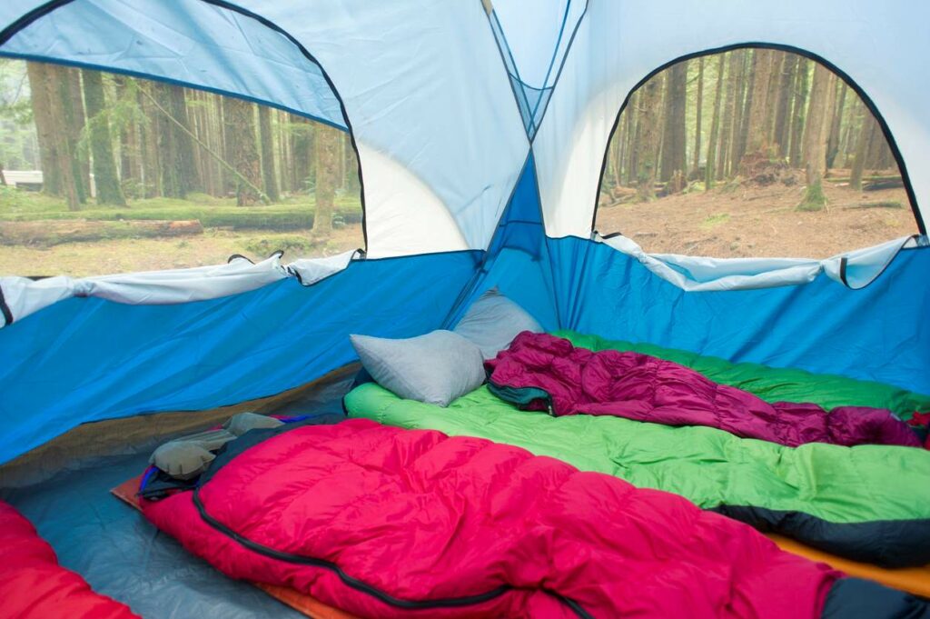 The interior of a tent with multiple colorful sleeping bags.