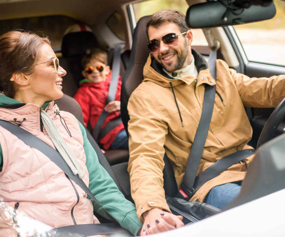 A happy family smiling in a car on a family vacation.