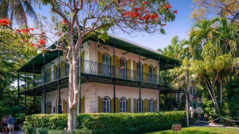 The Ernest Hemingway Home and Museum surrounded by trees in Key West, FL.