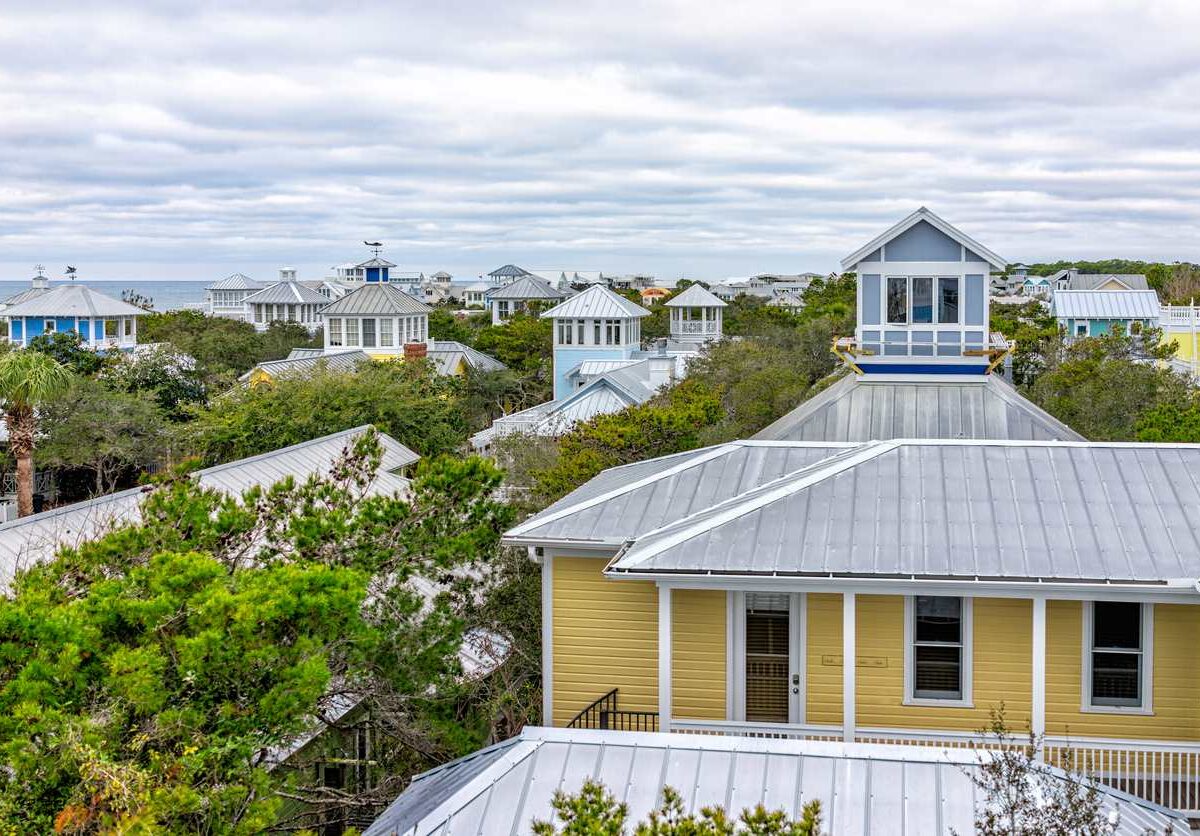 The tops of trees and houses in Seaside, FL, in winter with clouds in the sky.