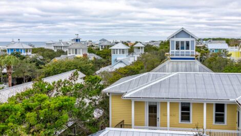 The tops of trees and houses in Seaside, FL, in winter with clouds in the sky.